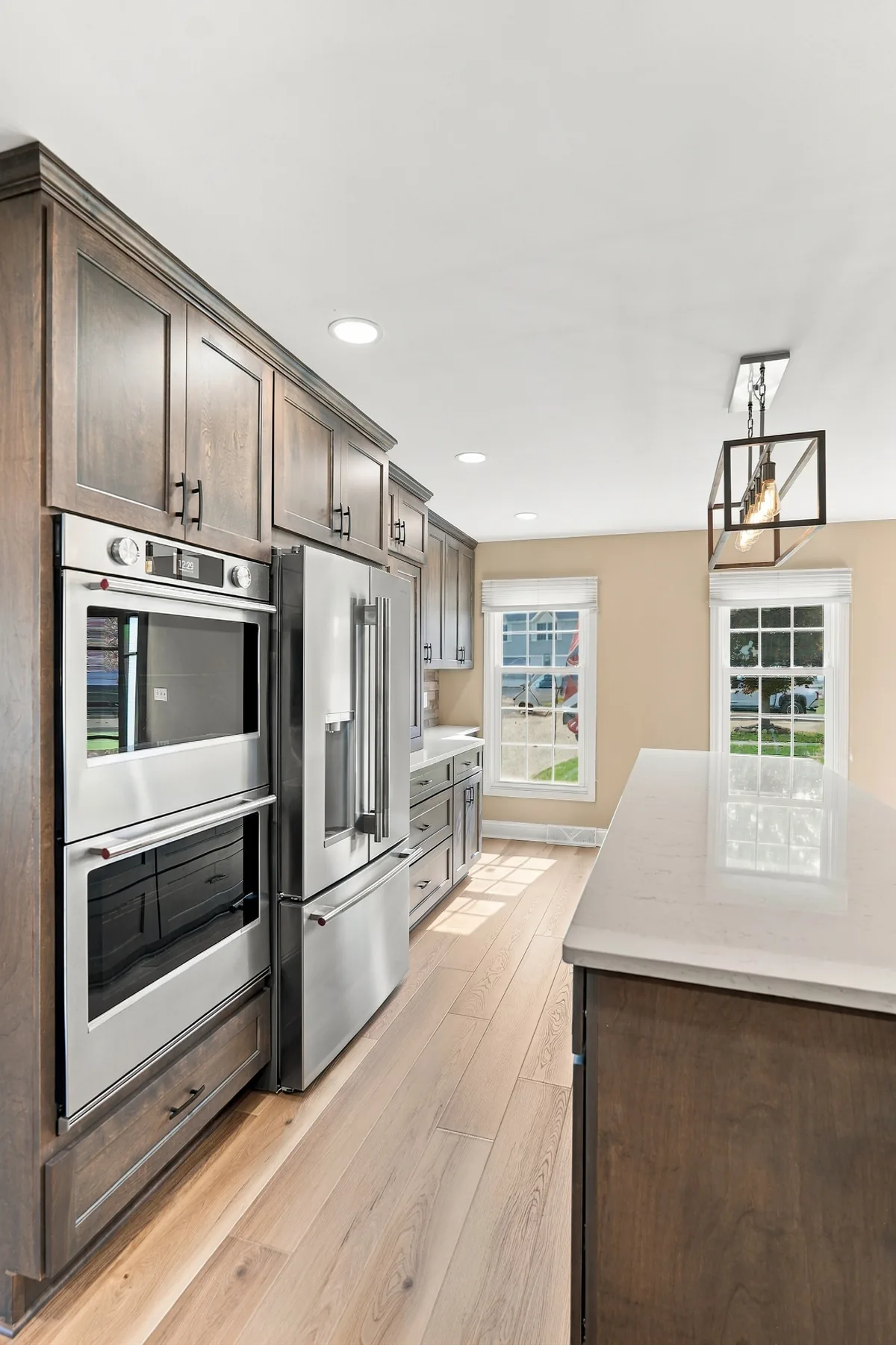 Double ovens and refrigerator beside the island in the Lancaster kitchen