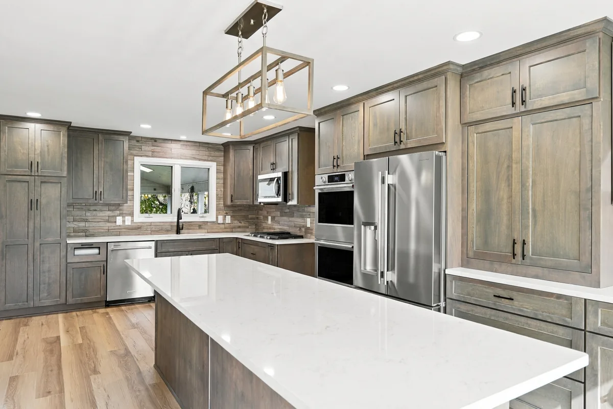 White island countertop, wood-tone cabinets, and pendant lighting in the finished Lancaster kitchen