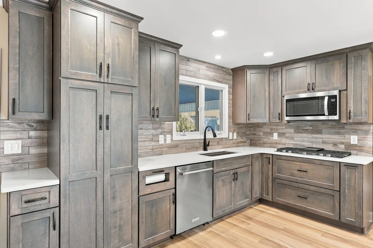 Sink and cooktop surrounded by wood-tone cabinetry and a patterned backsplash